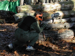  原木后面的彩弹射击运动员 